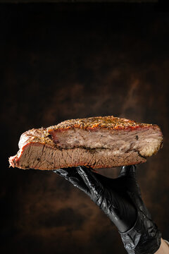 sliced smoked beef brisket with seasoned bark and smoke ring. Barbecue meat on dark rustic background.