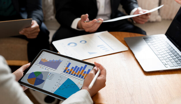 Business Team Analyzing Financial Data Charts on Digital Tablet and Laptop