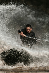 Fototapeta premium Man with sword stands in water while splashing waves around him during a dynamic action scene