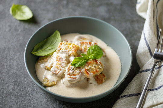 Homemade Potato Gnocchi in Creamy sauce with Basil leaves and parmesan Cheese in plate on the table