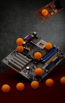 Still life with computer boards and orange balls on a red table.