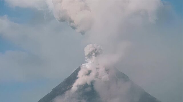 Majestic volcano erupting with thick plumes of smoke against a clear blue sky
