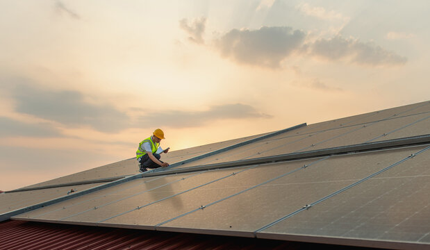 Solar panel technician inspects rooftop panels at dusk