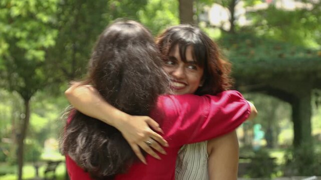 Young Indian Gen Z women friends sharing a joyful hug outdoors in a sunny green park, representing friendship, emotional support, happiness, social connection, youth culture, modern lifestyle