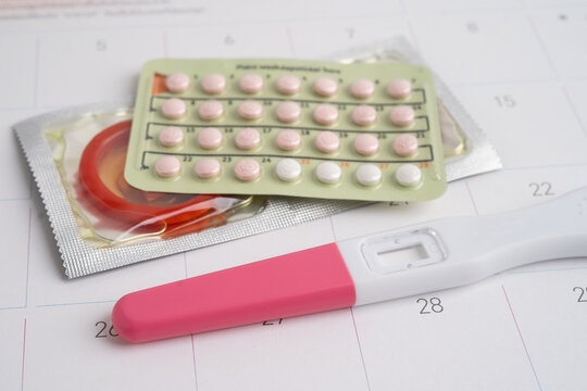 Pregnancy test and condom for female on calendar, ovulation day.