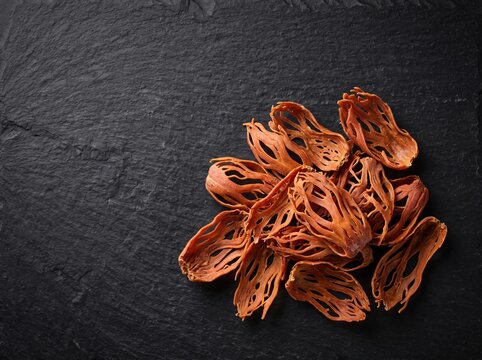 Mace spice arils arranged in pile on black slate surface