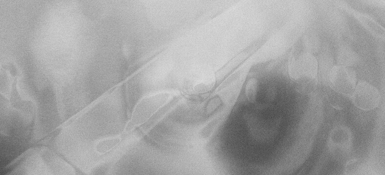Close-up abstract view of translucent fabric folds and subtle circular patterns in grayscale, hinting at texture and depth