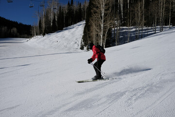 Skier Carving a Groomed Run Beneath Aspen Trees and Chairlift © Taras Vovchuk
