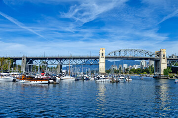 Fototapeta premium Burrard Bridge spans over a busy marina filled with sailboats and yachts, Granville Island,Aquabus Ferry Dock, Vamcouver, BC, Canada 