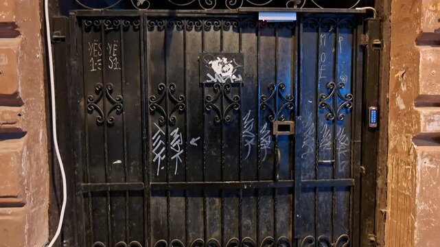 Ornate black wrought iron door set in a historic stone facade, featuring decorative scrollwork, aged textures, metal details, and a distinctive vintage architectural character
