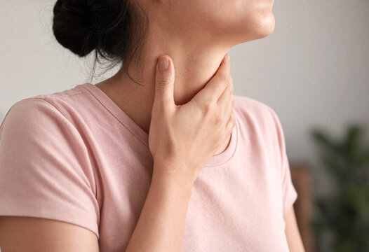 Woman touching neck area indicating possible discomfort or sore throat