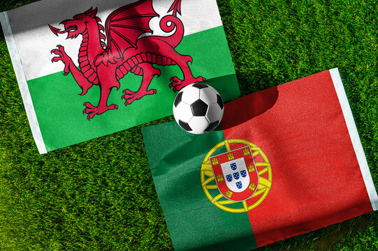 Wales vs. Portugal football match. National flags on green grass with soccer ball in the middle. Football background for international match.