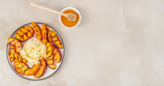 Grilled peach slices arranged on a plate with creamy cheese and honey in a small bowl, set against a light textured background