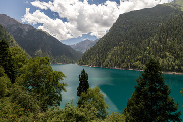 Obraz premium Turquoise Mountain Lake Surrounded by Forested Peaks in Jiuzhaigou, China