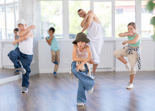 Young boys and girls in casual wear performing hip hop at group dance class in choreographic studio