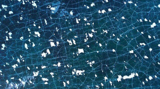 Cracked blue ice surface frozen lake backdrop. Aerial drone view of winter texture, white snow patterns. Natural climate background for cold weather, environment travel concept.