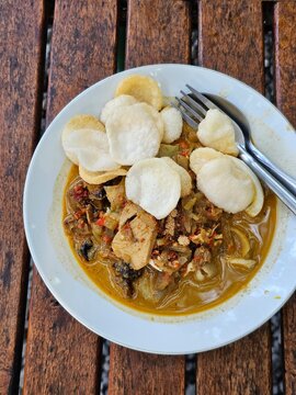 Lontong Cap Go Meh, a traditional Chinese-Indonesian Peranakan dish consisting of compressed rice cakes served with chicken opor, vegetable lodeh, spicy liver, and egg, served in a white bowl