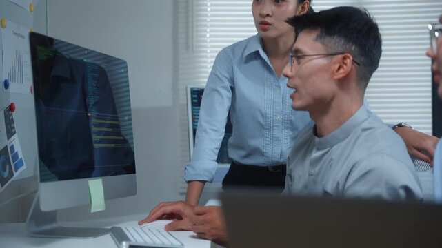 Collaborative asian software developers brainstorming ideas and programming on a computer screen in an office at night
