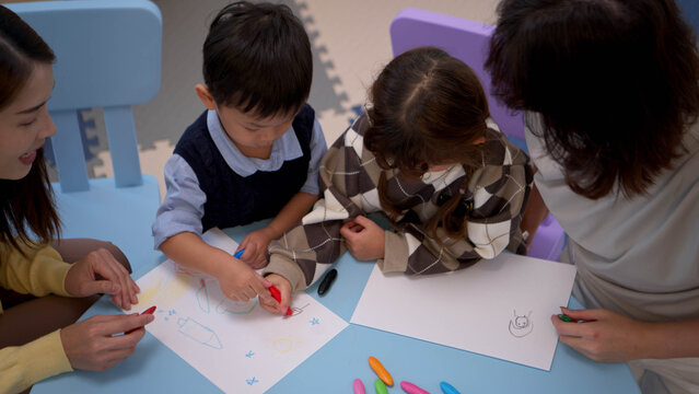 Teacher and parent guiding children in an art activity, promoting learning and creative thinking skills