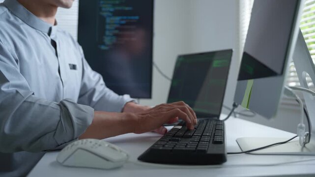 Software developer hands coding and typing on a computer keyboard while programming a new application in a modern office