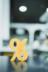 Obraz na płótnie Canvas Percentage discount sign wooden icon on reflective table with blur bokeh background, representing banking interest rate, financial tax ratio, retail sale promotion, and investment return concept.