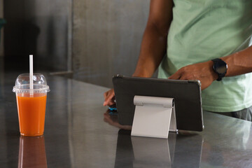 Tablet sitting on foldable stand and clear cup resting on reflective steel counter at kiosk © WavebreakMediaMicro