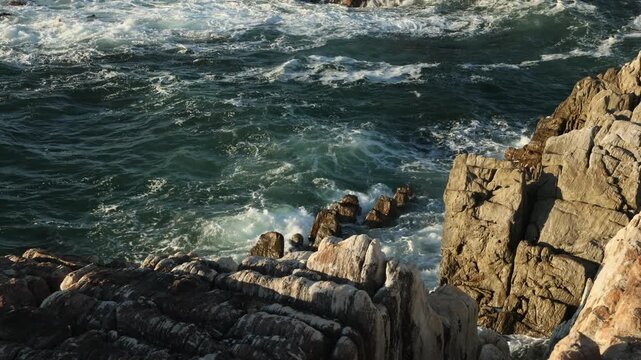 late afternoon light falling upon the rocky coastline of DeKelders with views toward Walker Bay Nature Reserve, South Africa