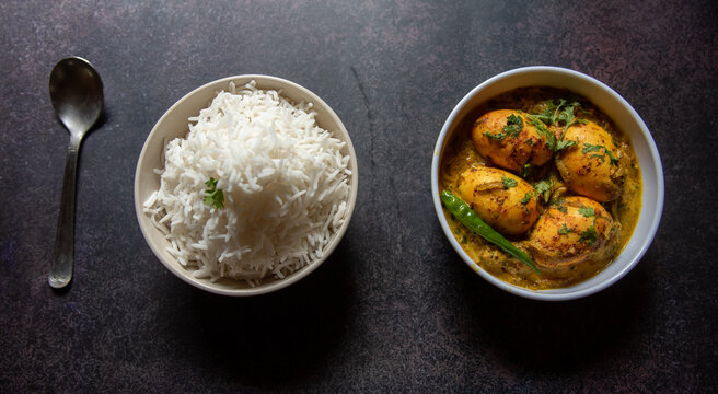 Cooked food rice and egg curry served in bowls. View from top, selective focus.