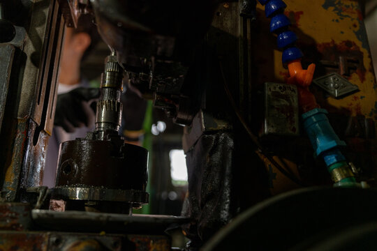 Traditional machine shop equipment in a vintage family metal workshop, dark detail of the drill chuck and round collet workpiece on the hobbing, equipment of a small family metalwork
