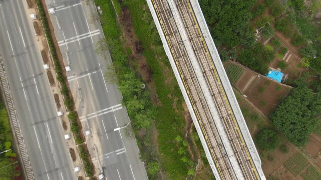 Aerial Top-Down View of Monorail Train on Elevated Track Beside Highway and Farmland