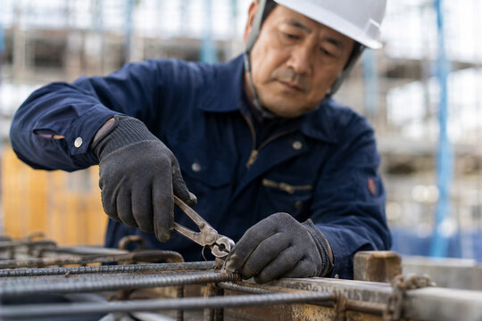 建設現場で工具を使い鉄筋の結束作業をする日本人建設作業員