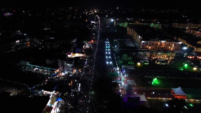 Aerial drone view of Vrindavan illuminated with colorful lights during Janmashtami at night. Crowded streets filled with devotees and visitors, while beautiful temples shine brightly.