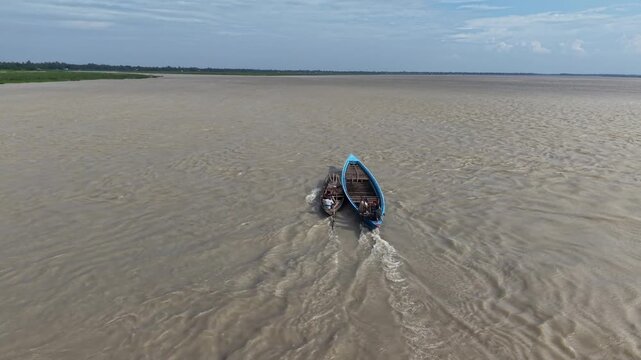 Aerial view of traditional wooden boats navigating a wide river in rural asia drone