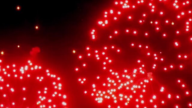 The footage shows bright fireworks in dark night sky. The view also shows bright red gold green or white sparks forming circular and branching light patterns within dark night sky.