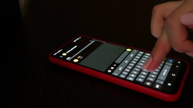 Woman's hand typing a text message on a smartphone keyboard. Close up of a finger touching the screen to write a chat. Concept of technology, social media and communication