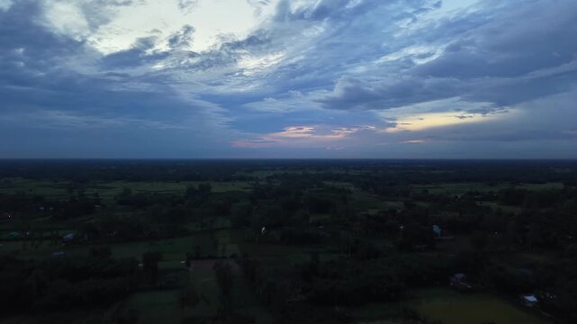 Aerial view of tropical rural landscape at twilight with dramatic storm clouds and serene horizon drone