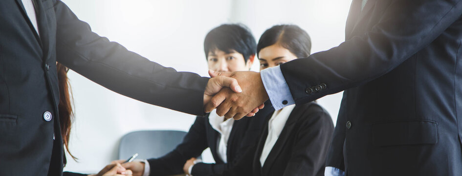 Business deal done. Business People shaking hands in the office after signed contract agreement.