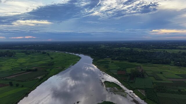 Aerial view of winding river through lush green farmland at sunset, cinematic landscape drone shot nature