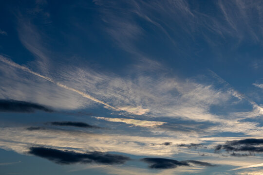 Cloud iridescence shining through wispy cirrus against a blue sky