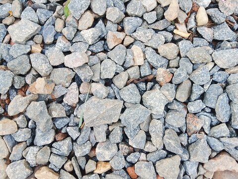 Granular grey ballast stones with scattered gravel on railway track bed background.