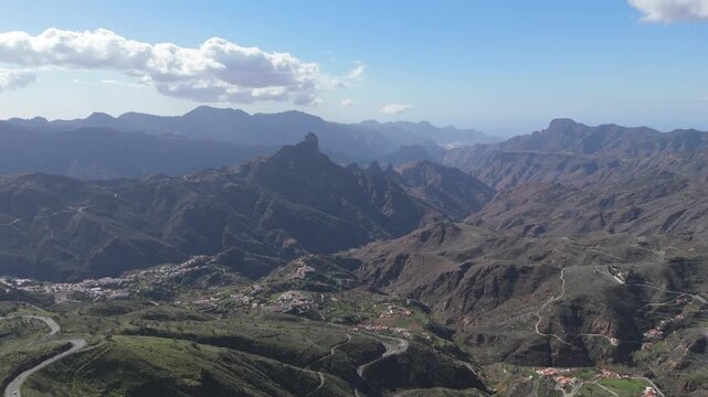 Aerial push in drone shot reveals the vast, rugged mountainous landscape of Gran Canaria. Explore the stunning barranco valleys and traditional houses of Tejeda village on this Canary Island.