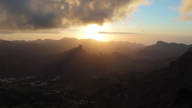 Aerial pan right drone view capturing a stunning sunset over the rugged mountains of Gran Canaria, on the Canary Islands, near the hamlet of El Majuelo.