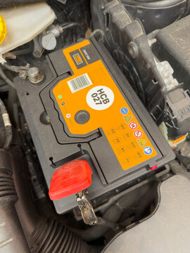 Winchester Hampshire England UK. 13.09.2026. Close-up view of a car battery labeled HCB 027, showing safety warnings and a barcode, situated within the vehicle's engine compartment
