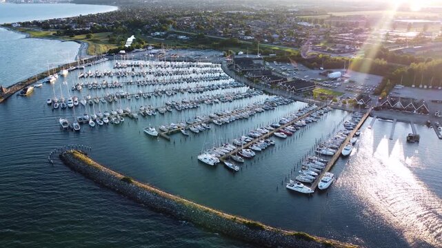 Ega Marina sailboat harbor enclosed by breakwaters near Aarhus, Denmark at sunset, aerial
