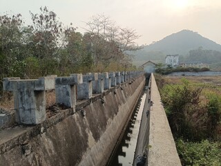 Fototapeta premium Concrete Water Irrigation Canal Leading Towards Hills