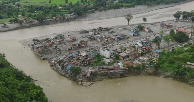 Nuwakot, Nepal, Aerial shot of extensive flash flood destruction, submerged riverside buildings, and heavy mud silt deposits surrounding a river confluence after a glacial outburst disaster