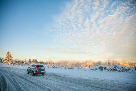 SUV drives down a snowy country road at sunrise