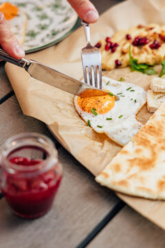 Person cutting into a sunny side up fried egg for breakfast