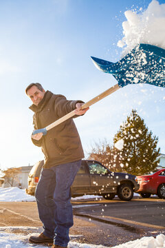 Smiling elderly man energetically shovels snow on sunny day