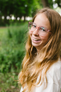 Happy girl with freckles and glasses smiling
